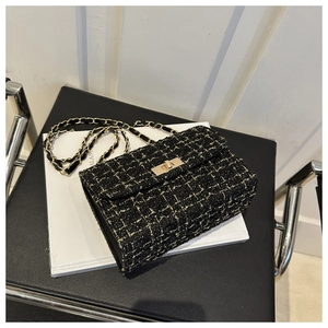Detail of tweed crossbody bag featuring black woven texture and golden chain strap
