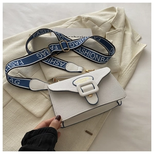 Detail of white square bag with blue trim, wide fabric strap, and Fashion Bags text
