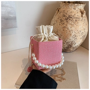 Detail of red and white woven bucket bag with large pearl handle and gold chain strap