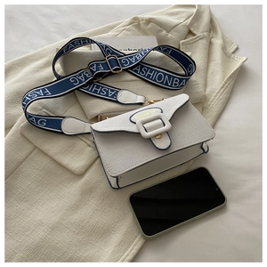 Detail of white mini square bag featuring gold buckle and stylish wide blue shoulder strap