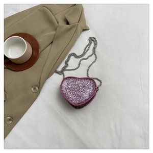 Detailed view of pink heart-shaped sequin mini bag with silver chain on fabric
