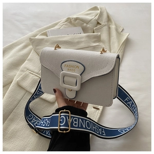 Detail of white canvas crossbody bag with wide blue fabric strap and metal buckle