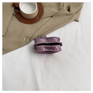 Detail of pink rhinestone mini bag with silver chain on beige suit jacket