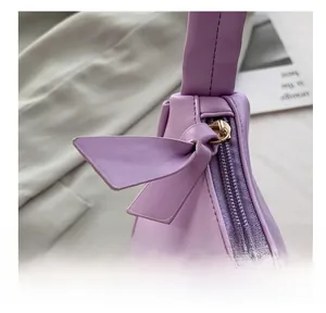 Detail showing smooth gold metal zipper and lavender leather knot on minimalist bag