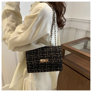 Close-up of black tweed plaid shoulder bag with gold chain and metal clasp detail