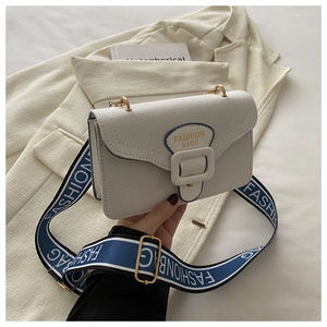Close-up of beige textured canvas crossbody bag with fashion gold lettering and strap