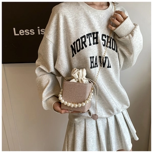 Detail of mini straw bucket bag with pearl handle and golden chain strap for summer