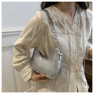 Silver hobo shoulder bag with metal chain strap and rivet details shown on model