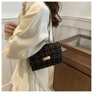 Classic black and gold tweed shoulder bag with metal chain strap worn by a model