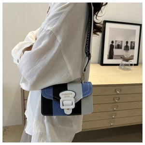 Detail der Crossbody-Tasche im Farblock-Design mit breitem Riemen und weißer Schnalle