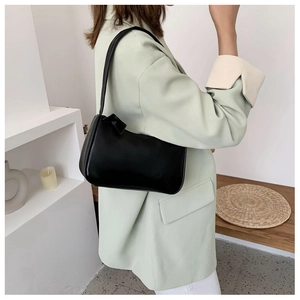 Chic minimalist black leather underarm bag worn by a model in a modern home setting