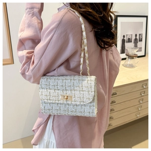 Classic white tweed chain bag worn on shoulder with metallic lock and refined texture