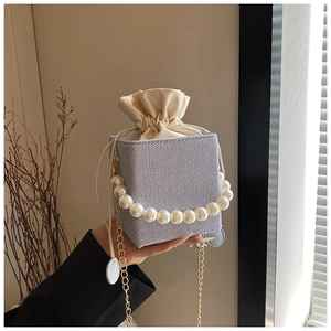 Detail of blue gingham fabric bucket bag with pearl handle and beige drawstring pouch