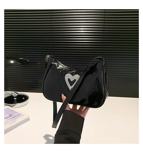 Detail of black patent leather shoulder bag with a sparkling rhinestone heart decoration
