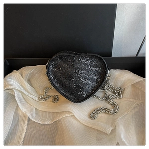 Detail of a heart-shaped bag with black sequins on white silk and a silver chain