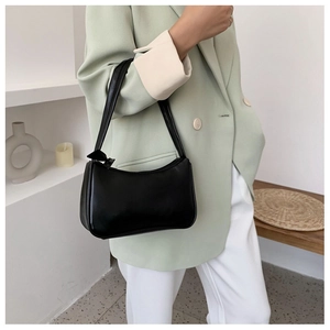 Side view of a black minimalist faux leather baguette bag worn over the shoulder