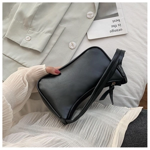 Detail of minimalist black baguette shoulder bag with smooth matte finish and zipper
