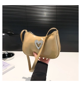 Detail of khaki baguette bag featuring a large heart rhinestone buckle and smooth finish