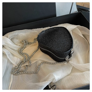 Detail of black heart-shaped sequin bag with silver chain in a luxury gift box