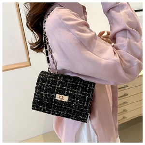 Close-up of black tweed crossbody bag with gold chain and metal turn-lock on model