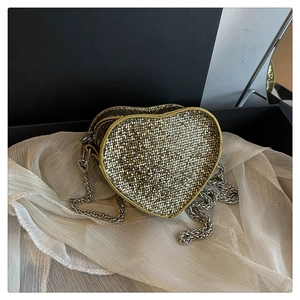 Sparkly gold heart-shaped evening bag with silver chain strap on white fabric