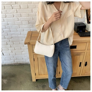 Close-up of minimalist ivory white faux leather underarm bag with smooth zipper closure