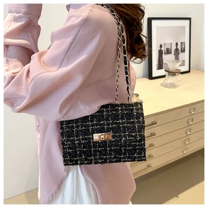 Close-up of black and gold tweed crossbody bag with golden chain and twist lock clasp