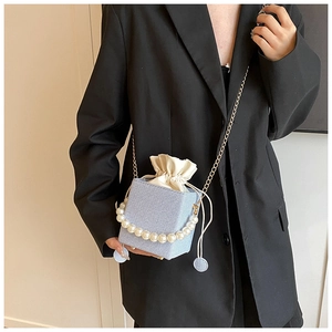 Detail of light blue textured bucket bag with pearl handle and golden chain strap
