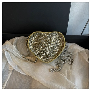Detail of heart-shaped evening clutch with sparkling gold rhinestones and silver chain