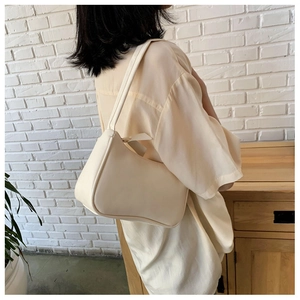 Close-up of cream white leather hobo bag worn by model against a bright natural background