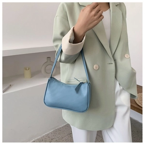Close-up of light blue leather baguette bag with zip closure and minimalist long puller