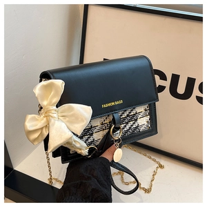 Detail of tweed拼接 shoulder bag with a satin bow and gold chain strap close-up