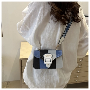 Detail of crossbody bag with blue stripes and wide strap showing FASHION BAGS text