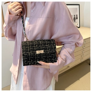 Fashionable black and gold tweed crossbody bag with chain strap worn by a model
