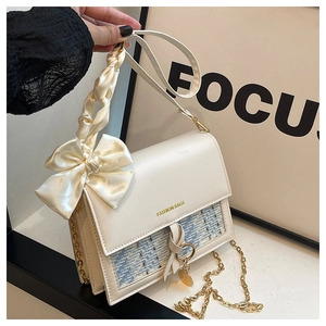 Detail of cream leather shoulder bag with blue tweed pattern and gold chain strap