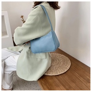 Minimalist light blue shoulder bag paired with a green blazer in a modern interior setting