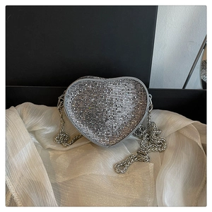 Detail of silver heart-shaped evening bag with glittering crystals and metal chain strap