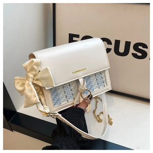 Detail of white and blue crossbody bag with ribbon bow and gold fashion lettering