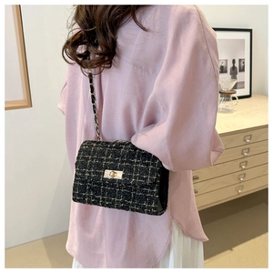 Rear view of a model wearing a black tweed chain bag with gold rectangular clasp and strap