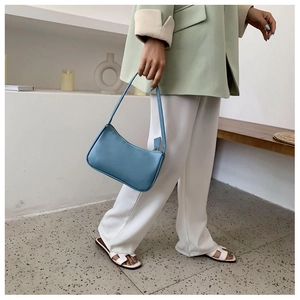 Detailed view of a light blue crescent underarm bag styled with a green blazer outfit