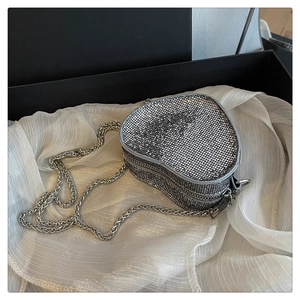 Macro detail of heart-shaped evening bag with silver rhinestones and chain strap
