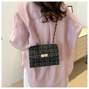Rear view of a model wearing the black tweed chain bag with gold metallic accents
