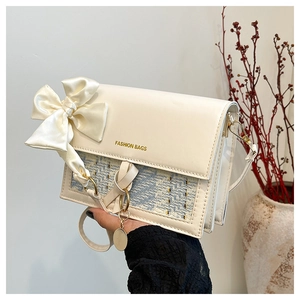 Detail of cream white leather bag with blue weave fabric and oversized satin bow accent