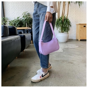 Detailed view of a purple baguette shoulder bag being held to show size and fit