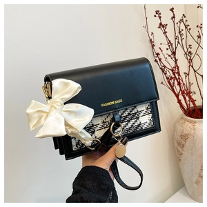 Detail of fashion crossbody bag with tweed texture and white silk bow accent