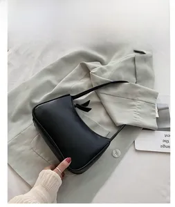 Detailed view of minimalist black leather baguette bag on stylish green blazer outfit