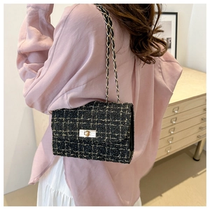 Close-up of elegant black tweed shoulder bag featuring gold thread and metal chain strap