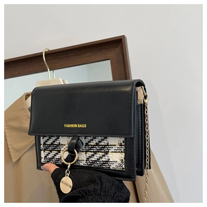 Close-up of structured black leather and houndstooth fabric shoulder bag with gold chain strap