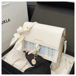 Detail of white and blue crossbody bag with gold chain and silk bow decoration