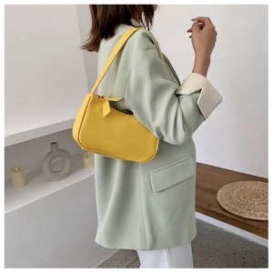 Close-up of minimalist bright yellow crescent shoulder bag with leather tassel detail